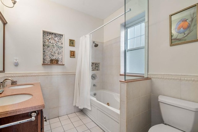 full bath with a wainscoted wall, toilet, tile walls, and tile patterned flooring