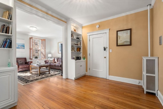 foyer featuring light wood-style floors, baseboards, and ornamental molding