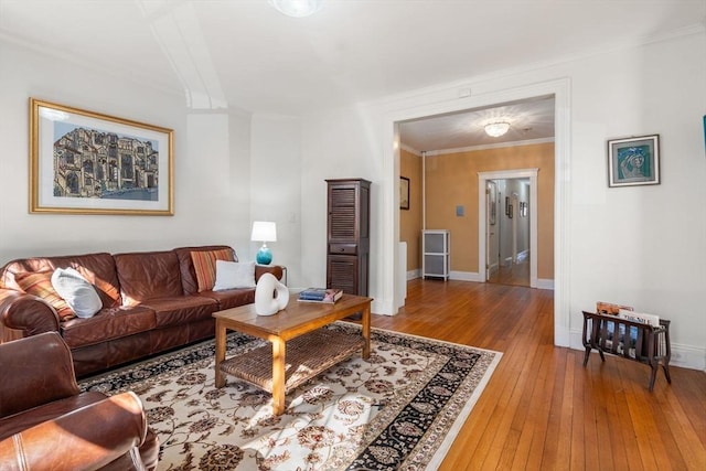 living room featuring crown molding, baseboards, and light wood-type flooring