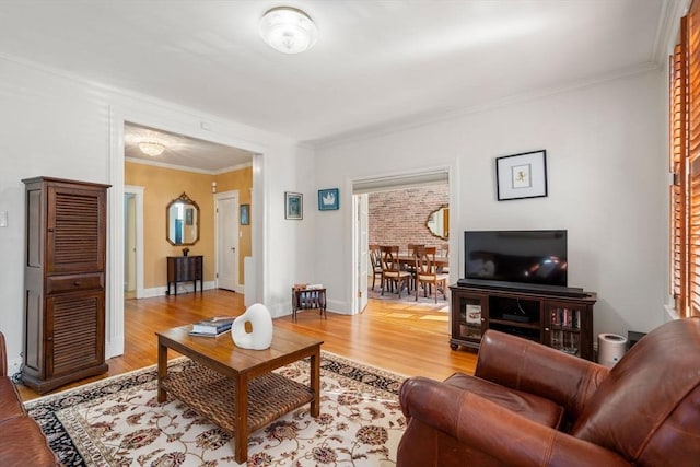 living room with light wood-type flooring, baseboards, and ornamental molding