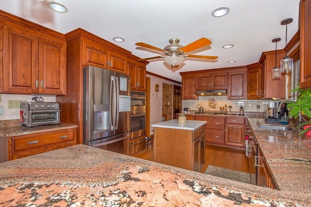 kitchen with stainless steel appliances, sink, pendant lighting, hardwood / wood-style floors, and a kitchen island