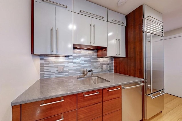 kitchen featuring appliances with stainless steel finishes, tasteful backsplash, light stone countertops, white cabinets, and sink