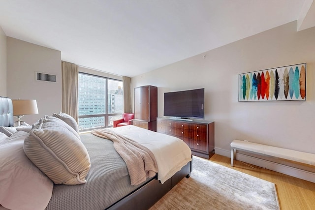 bedroom with light wood-type flooring and expansive windows