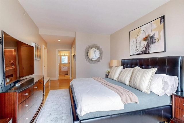 bedroom with ensuite bath and light hardwood / wood-style flooring