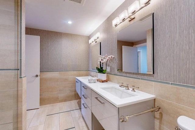 bathroom with toilet, tile patterned floors, tile walls, and vanity