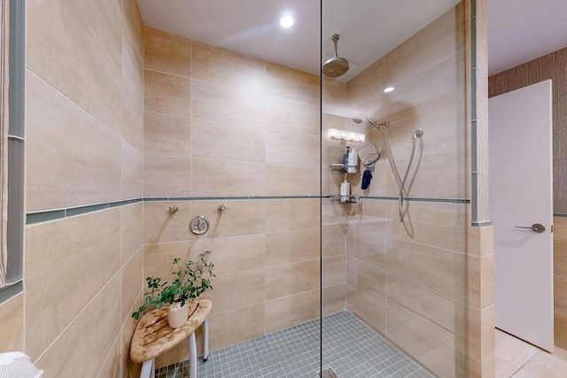 bathroom with a shower with door and tile walls