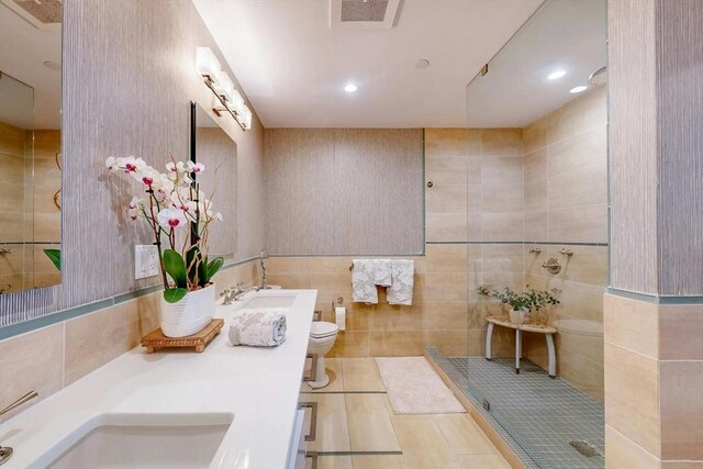 bathroom with tile patterned flooring, an enclosed shower, double sink vanity, tile walls, and toilet