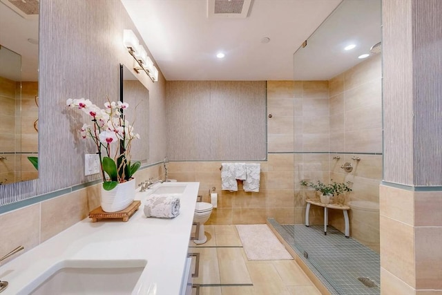 bathroom with tile walls, tile patterned flooring, a tile shower, and toilet