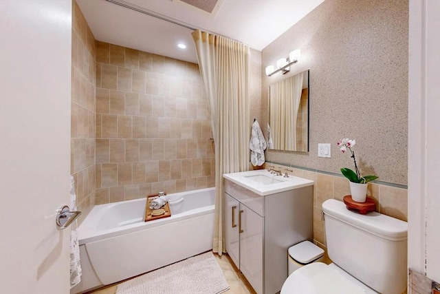 full bathroom featuring tile walls, tiled shower / bath combo, vanity, and toilet