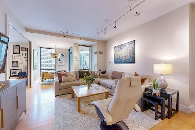 living room with light hardwood / wood-style flooring, a chandelier, and track lighting