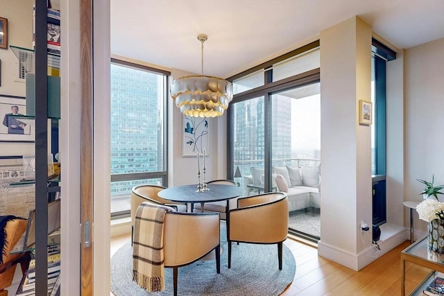 dining space featuring floor to ceiling windows, a chandelier, a wealth of natural light, and light hardwood / wood-style flooring