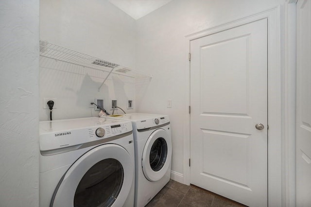 washroom with washing machine and clothes dryer and dark tile patterned flooring