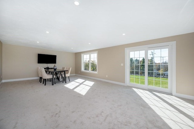 unfurnished dining area featuring light colored carpet and plenty of natural light