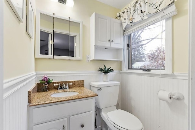 bathroom featuring a wainscoted wall, vanity, and toilet