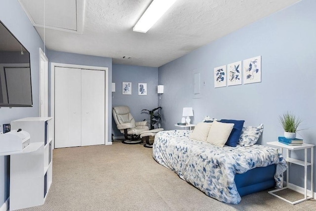 carpeted bedroom with attic access, a closet, visible vents, and a textured ceiling