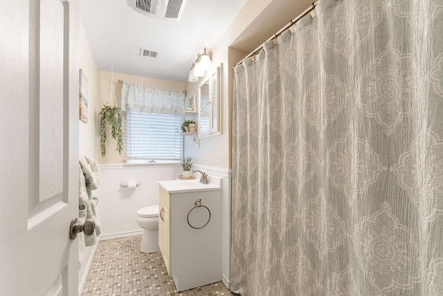 full bath featuring toilet, wainscoting, visible vents, and vanity