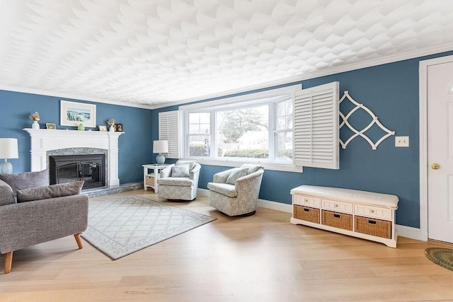 living area featuring ornamental molding, wood finished floors, a high end fireplace, and baseboards