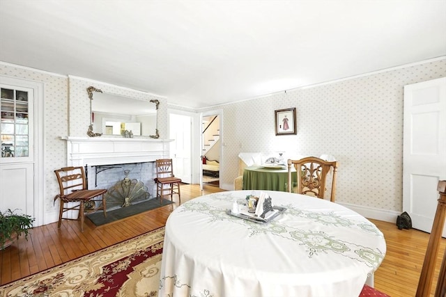 96 College St, South Hadley, MA 01075 - dining room with light wood-type flooring, stairway, ornamental molding, a fireplace with flush hearth, and wallpapered walls