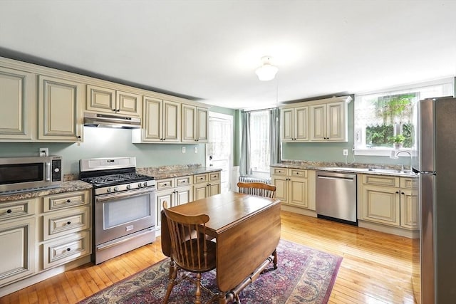 96 College St, South Hadley, MA 01075 - kitchen with cream cabinetry, appliances with stainless steel finishes, under cabinet range hood, light wood-style floors, and a sink