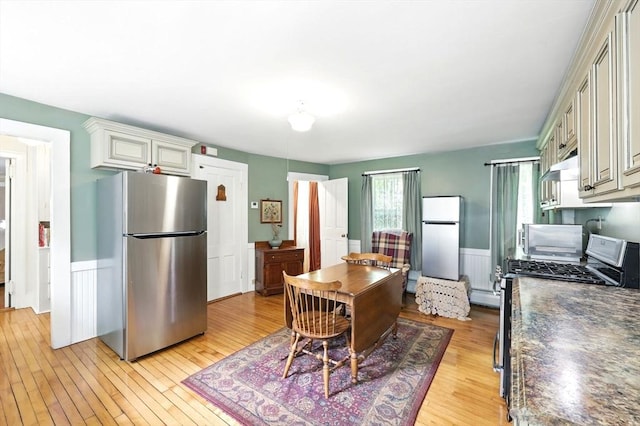 96 College St, South Hadley, MA 01075 - kitchen featuring stainless steel appliances, dark countertops, light wood-style flooring, a wainscoted wall, and baseboard heating