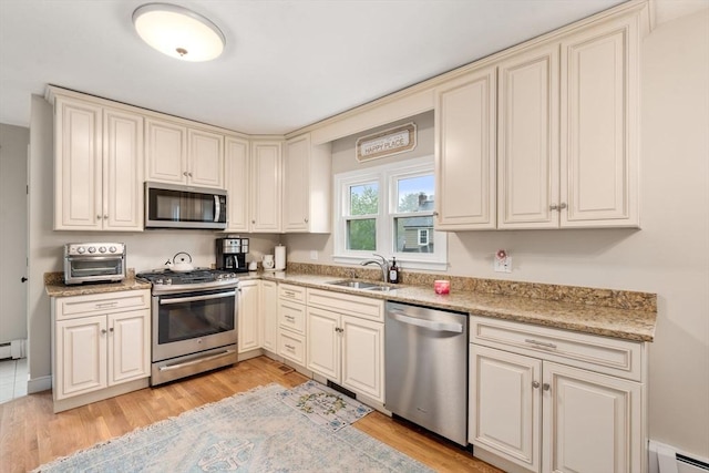 137 Pond, Westwood, MA 02090 - kitchen with stainless steel appliances, baseboard heating, a sink, cream cabinets, and light wood-style flooring