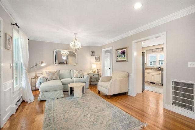 137 Pond, Westwood, MA 02090 - living area with light wood-type flooring, a chandelier, baseboard heating, a baseboard heating unit, and crown molding