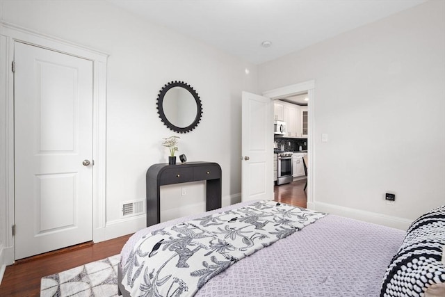 bedroom featuring visible vents, baseboards, and wood finished floors