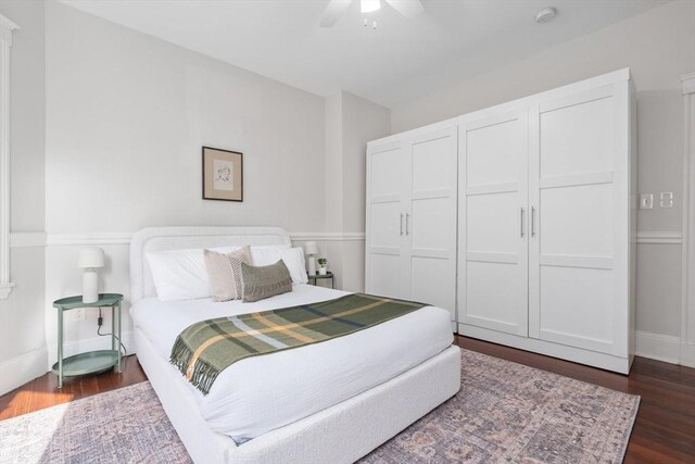 bedroom with dark wood-type flooring, a ceiling fan, a closet, and baseboards