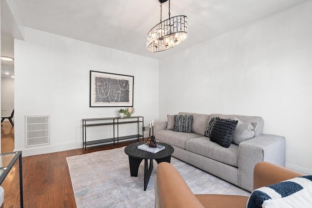 living room featuring visible vents, an inviting chandelier, baseboards, and wood finished floors