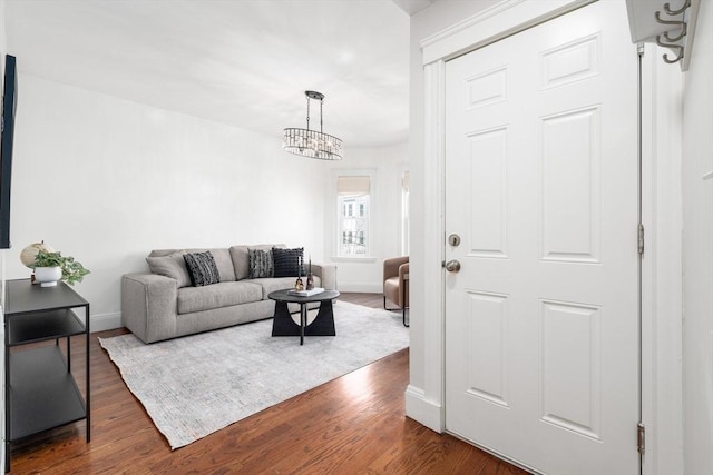 living area with a chandelier, baseboards, and dark wood-style floors