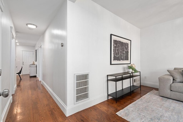 hallway featuring visible vents, baseboards, and wood finished floors