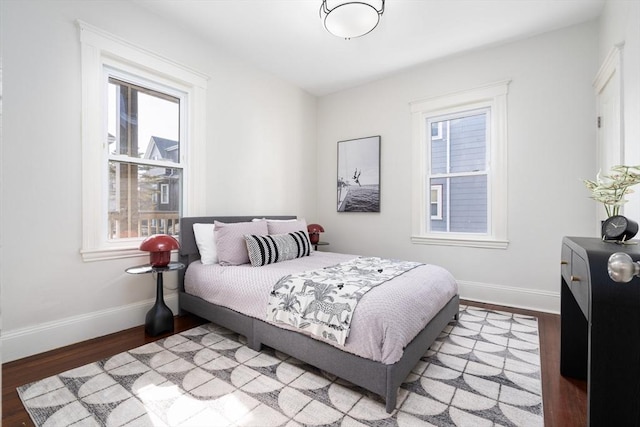 bedroom with multiple windows, baseboards, and wood finished floors