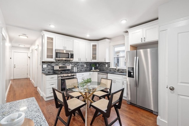 kitchen featuring decorative backsplash, appliances with stainless steel finishes, dark wood-style floors, white cabinets, and a sink