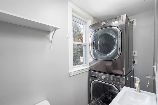 clothes washing area featuring laundry area, stacked washer / drying machine, and a sink