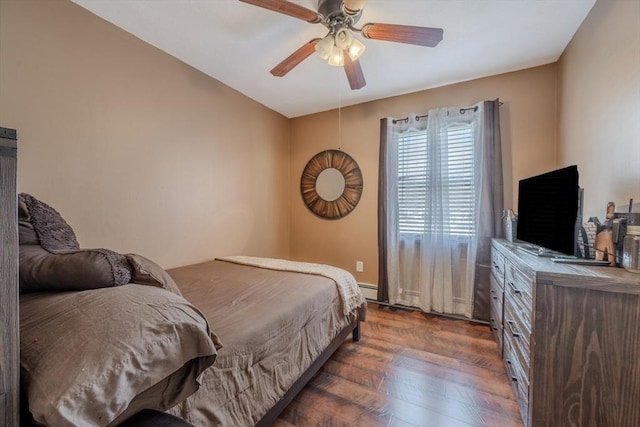 bedroom featuring a baseboard heating unit, dark wood finished floors, and a ceiling fan