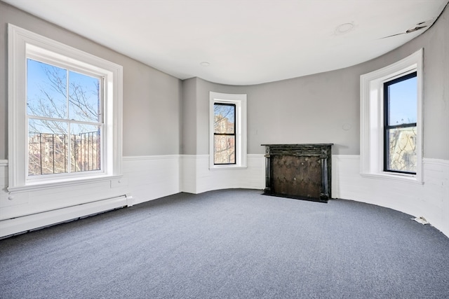 unfurnished living room featuring plenty of natural light, dark carpet, and baseboard heating