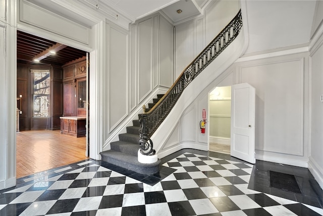 stairway with ornamental molding, beamed ceiling, and dark tile flooring