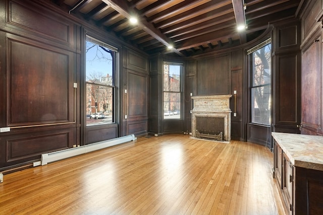 interior space with light stone counters, beam ceiling, dark brown cabinetry, and light hardwood / wood-style flooring