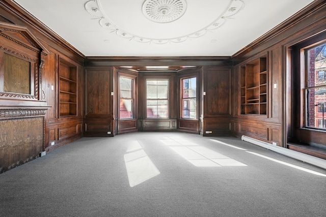 empty room featuring built in shelves, ornamental molding, and light carpet