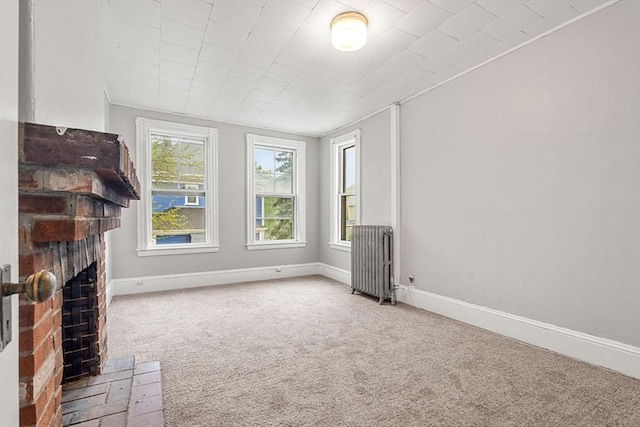unfurnished living room featuring radiator heating unit, carpet floors, a fireplace, and baseboards