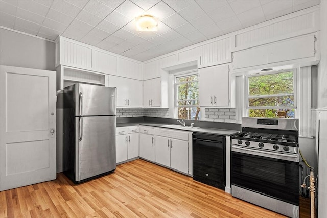 kitchen featuring stainless steel appliances, dark countertops, a sink, and white cabinets