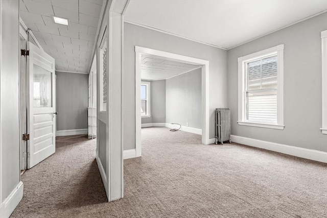 spare room featuring carpet flooring, ornamental molding, baseboards, and radiator heating unit