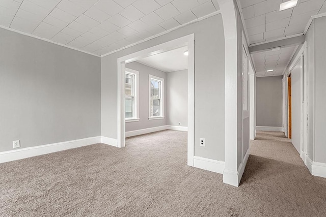carpeted spare room with crown molding and baseboards
