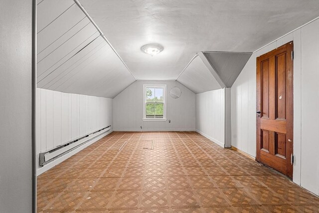 bonus room with a baseboard heating unit, vaulted ceiling, and baseboards