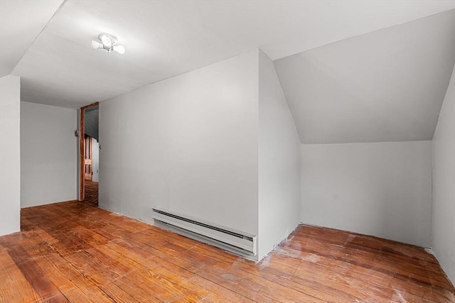 additional living space featuring a baseboard radiator, vaulted ceiling, and wood-type flooring