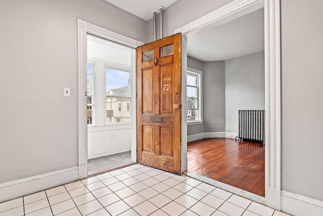 entrance foyer featuring radiator heating unit, baseboards, and light tile patterned flooring