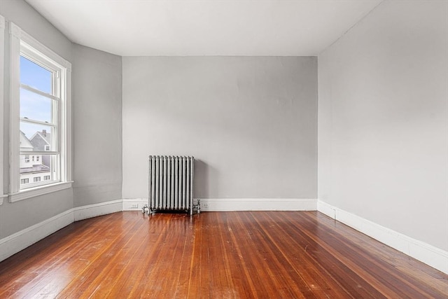 empty room with radiator, wood-type flooring, and baseboards