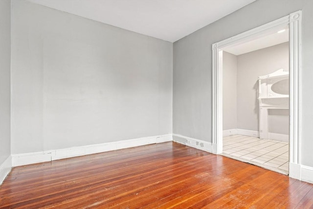 spare room with hardwood / wood-style floors and baseboards
