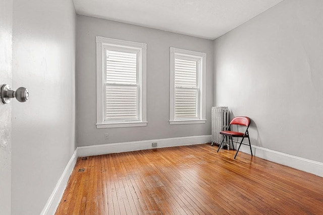 living area featuring radiator heating unit, hardwood / wood-style flooring, and baseboards