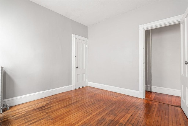spare room with wood-type flooring and baseboards
